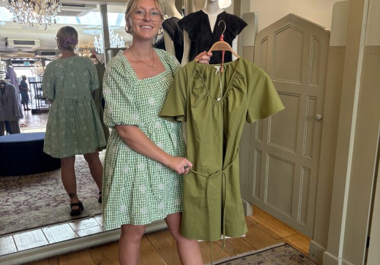 Harriet shopping and holding up a green dress