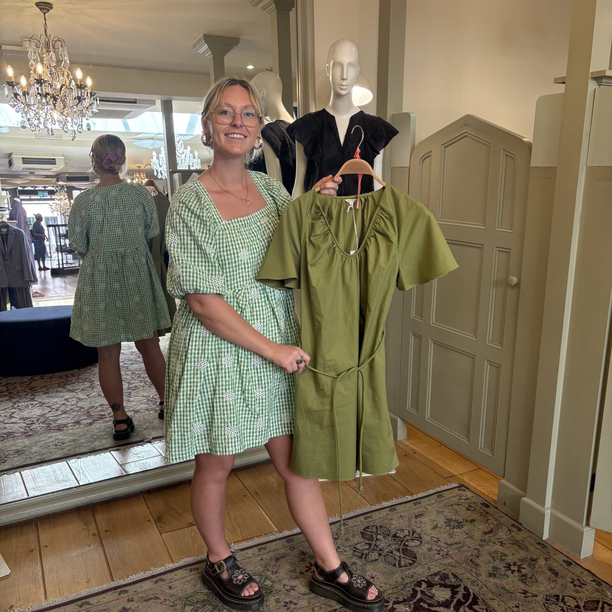 Harriet shopping and holding up a green dress